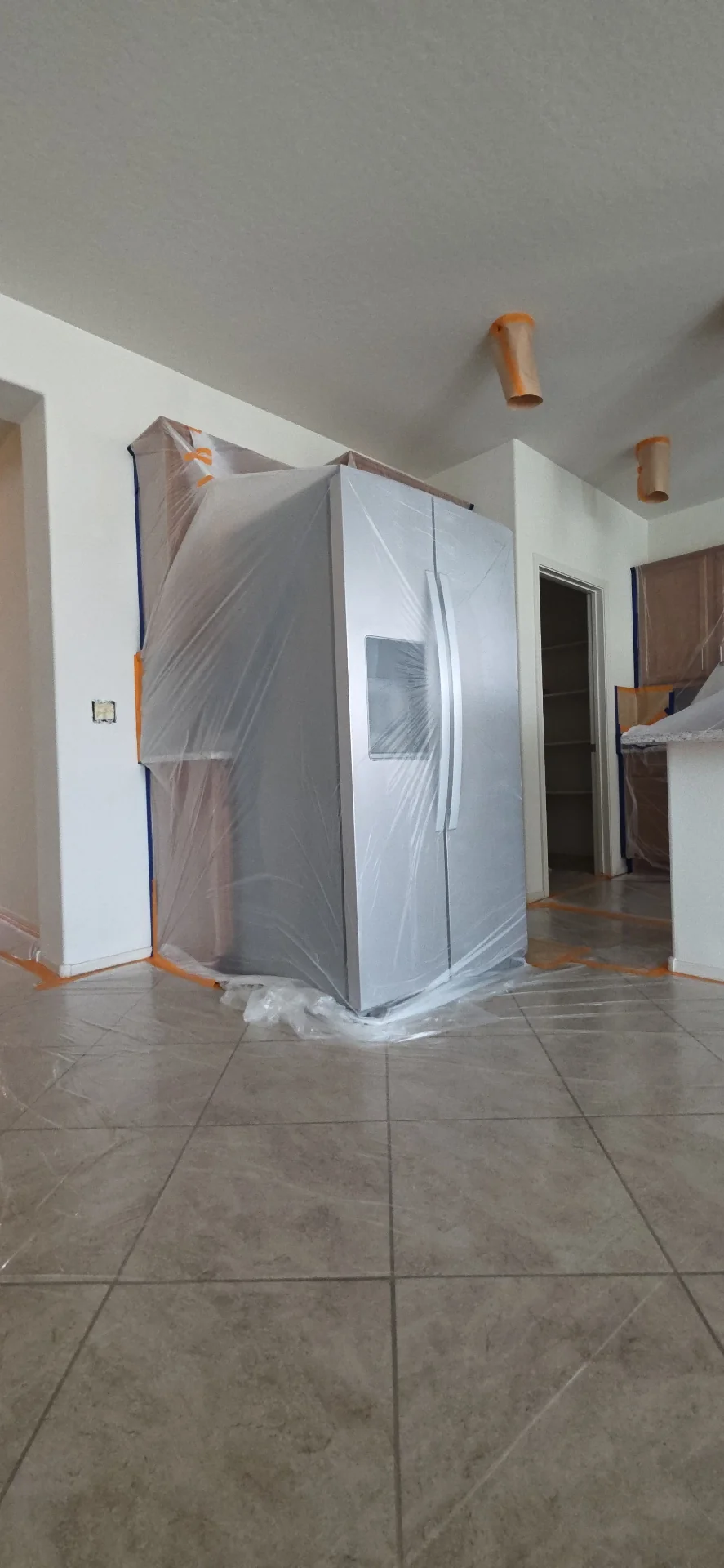Refrigerator draped in plastic to protect appliances during an interior repaint