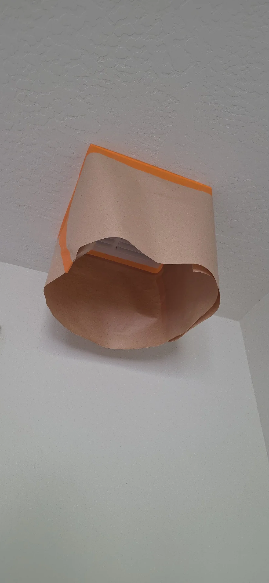Ceiling vent masked with paper and orange tape before spraying in a West Valley home