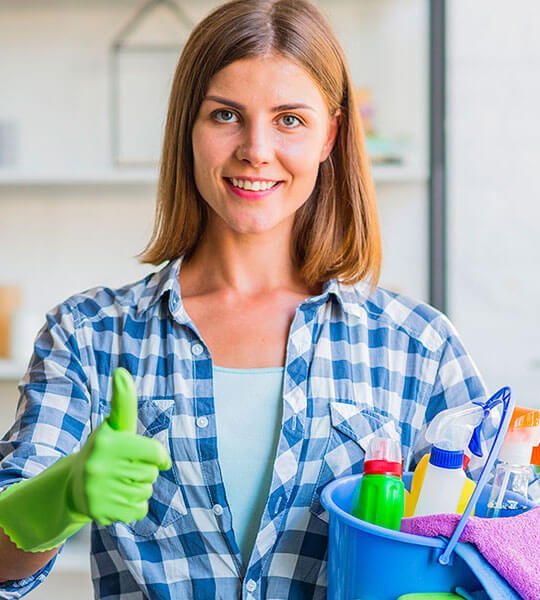 Woman in green gloves giving a thumbs up, holding a cleaning bucket with various cleaning supplies, symbolizing satisfaction and service quality in painting and cleaning solutions.