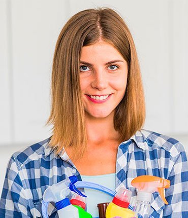 Woman smiling while holding various cleaning supplies, representing professional cleaning services offered by Desert Mesa Painting.