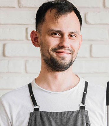 Smiling man in an apron, representing a team member at Desert Mesa Painting, specializing in quality painting services.